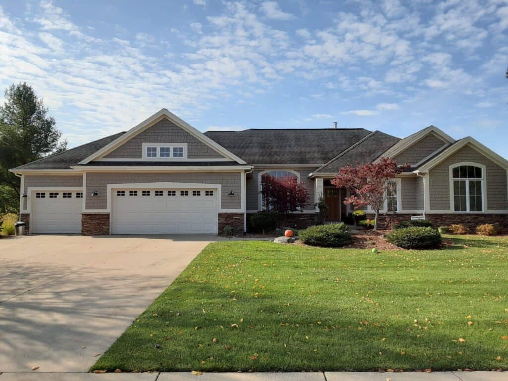 Vibrant house exterior painted with a neutral color palette, featuring a manicured lawn, decorative trees, and updated windows, showcasing professional residential painting services from Thornapple Painting.