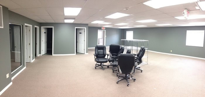 Modern office conference room with black ergonomic chairs, glass partitions, and soft gray walls, perfect for meetings and collaborative work at Thornapple Painting.