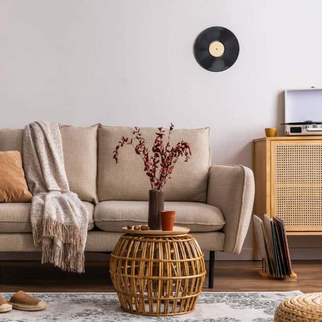 Elegant living room with beige sofa, modern rattan coffee table, and vintage record player, featuring stylish home decor and accent pieces for a cozy, trendy atmosphere.