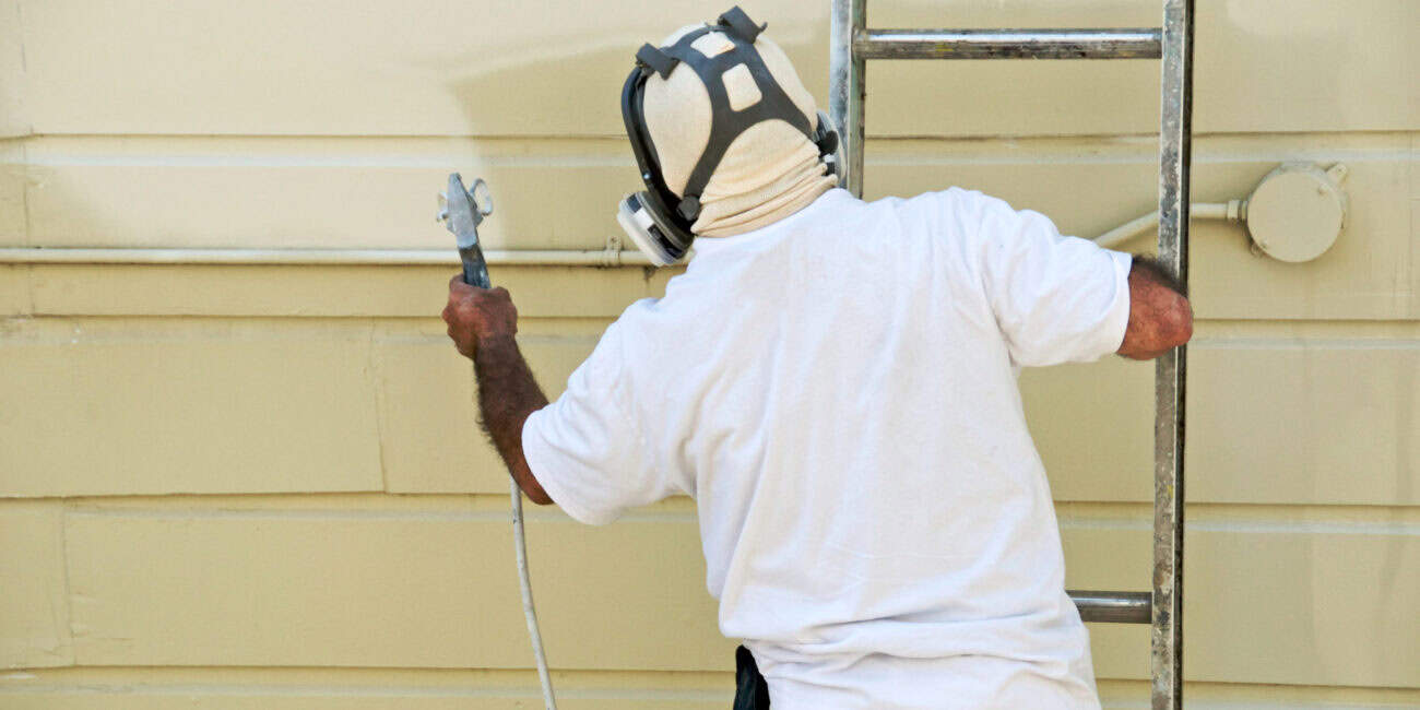 High-quality house painter working on exterior siding with scaffolding, showcasing professional painting services for residential homes, ensuring a smooth and durable finish.
